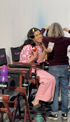 two women are sitting in chairs and one is combing another woman's hair