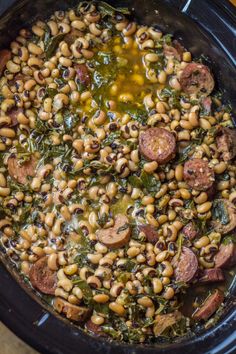 a crock pot filled with beans, sausage and spinach