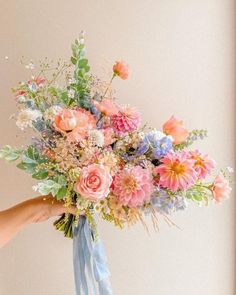 a person holding a bouquet of flowers in their hand with the other hand on it