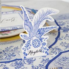 a table topped with blue and white plates covered in paper cutout birds on top of each other