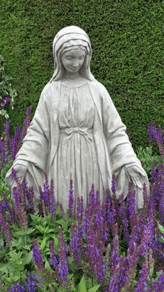 a statue is surrounded by purple flowers