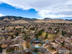 an aerial view of a residential area with mountains in the background and a blue circle at the center