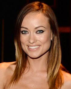 a beautiful young woman wearing a strapless dress smiling at the camera with blue eyeshadow