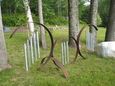 several metal sculptures in the grass near trees