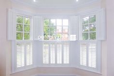 a corner window with white shutters in an empty room