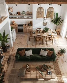 an overhead view of a living room and dining area with couches, coffee table, potted plants and kitchen in the background