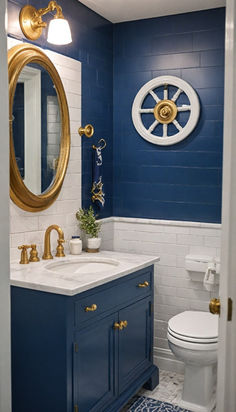 a blue and white bathroom with gold accents on the wall, toilet, sink and mirror