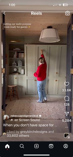 a woman standing in the middle of a room with a light on above her head