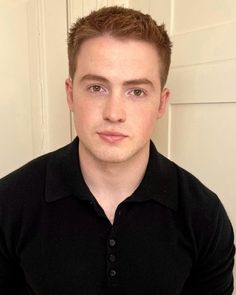 a young man in a black shirt is posing for the camera