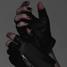 a woman's hands with black nail polish holding up her glove