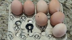 an egg carton with six eggs in it on a counter top next to some stencils