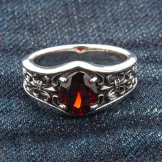 Refined, elegant, and intricate, the style of baroque will appeal to sophisticated men who are not afraid to wear ornate patterns and bright accents. The key element of this Garnet Sterling Silver Band ring is a large blood-red faceted garnet that successfully complements the contrasting colors of polished and blackened silver. A heraldic lily, otherwise knows as fleur de lis, blooms on the sides of the stone. For several centuries, it has been considered a symbol of royal power. Fortunately, yo Blood Ring, Red Garnet Ring, Style Baroque, Dragon Bracelet, Garnet Gem, Gothic Rings, Sterling Silver Rings Bands, Braided Leather Bracelet, Red Band