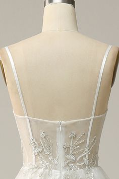 the back of a white wedding dress on a mannequin headdress with beading