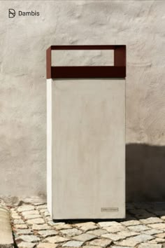 a white and brown trash can sitting in front of a wall