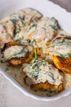 chicken with sauce and herbs in a white dish