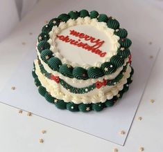 a three layer cake with white frosting and green decorations