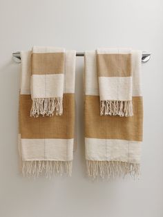 two tan and white towels hanging on a towel rack