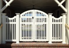 an open white gate with brick steps leading up to the front door and side entrance