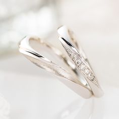 two white gold wedding bands with diamonds on them sitting on top of a glass table