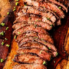 steak sliced up on a cutting board with parsley sprinkled around the edges