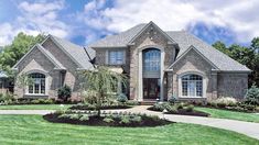 a large brick house with lots of windows and landscaping around the front door, on a sunny day