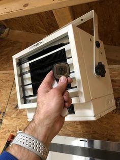 a man is holding an air conditioner in his hand and pointing it at the ceiling