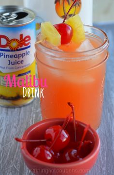 two glasses filled with drinks sitting on top of a table next to cans of pineapple juice