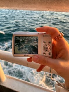 a person is holding up a camera to take a photo on the deck of a boat