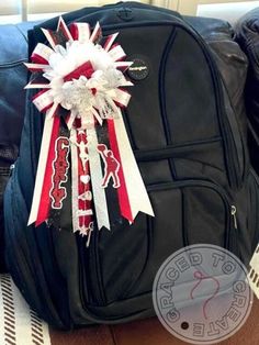 a black backpack with red, white and blue ribbons on the front is sitting on a table