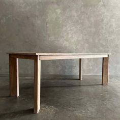 a wooden table sitting on top of a cement floor in front of a concrete wall