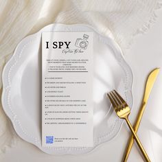 a white plate topped with a menu next to a gold fork and knife on top of a table