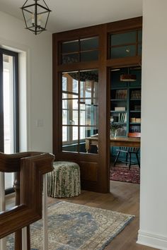 a living room filled with furniture next to a window covered in bookshelves and a rug