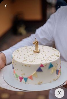 a person holding a cake with a number one on it