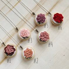 six necklaces with different colored flowers in them on a table next to each other