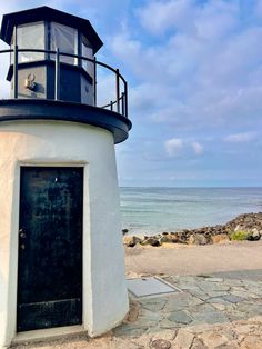 a white and black light house next to the ocean