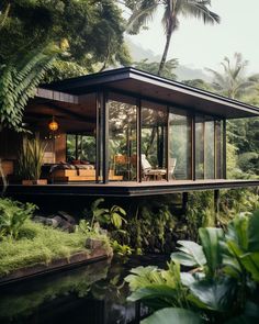 the house is surrounded by lush green trees and plants, along with a small pond