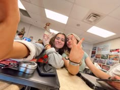 two young women sitting at a counter making the peace sign