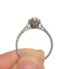 a hand holding an old - fashioned diamond ring with filigrees on it