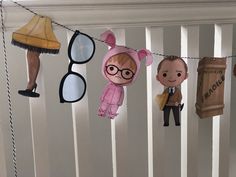 some paper dolls are hanging from a line with clothes and eyeglasses on them