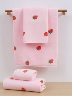 pink towels with strawberries on them hanging from a towel rack next to two folded ones