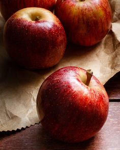 three red apples sitting next to each other on top of a piece of wax paper