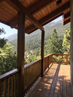 a wooden porch with railings and trees in the background