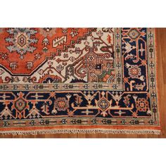 an antique persian rug with blue, orange and white colors on wood flooring area