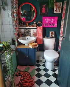 a bathroom with black and white checkered flooring, green walls and pink accents