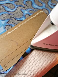 a pink iron sitting on top of a piece of fabric next to a cardboard box