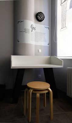 a small stool sits in front of a desk with a poster on the wall behind it