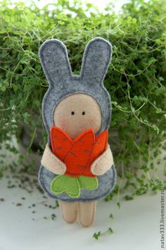 a stuffed rabbit holding a red heart sitting in front of some green plants and bushes