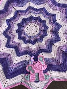 a crocheted baby blanket with a teddy bear on the bottom and purple stripes