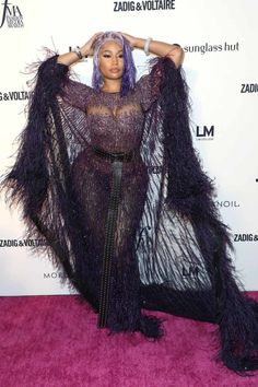 nicki mina is wearing a purple dress with black fringes on the sides and her hands behind her head