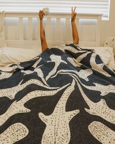 a person laying on top of a bed under a black and white bedspread